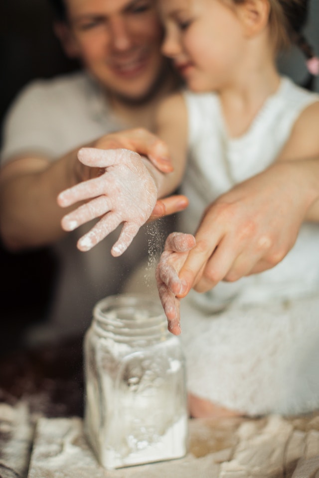 Father helping daughter get flour off her hands