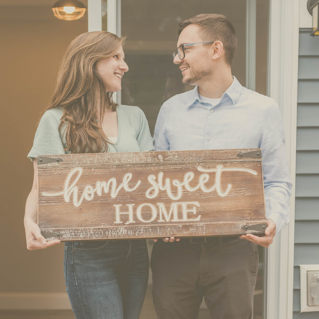 Young couple holding home sweet home wooden sign